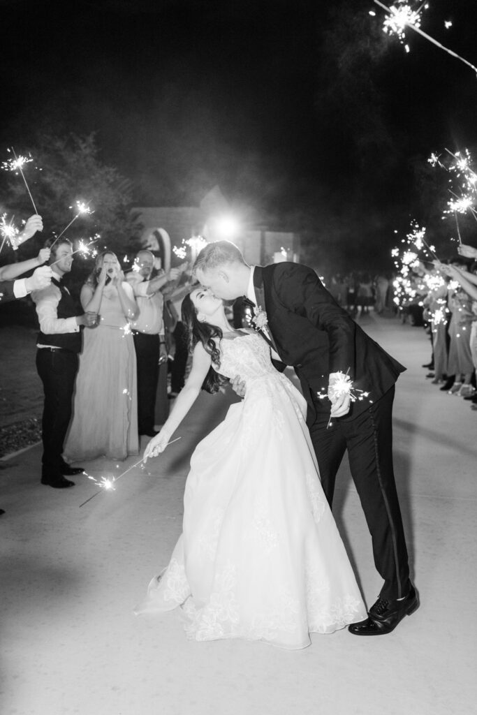 bride and groom kissing while holding sparklers
