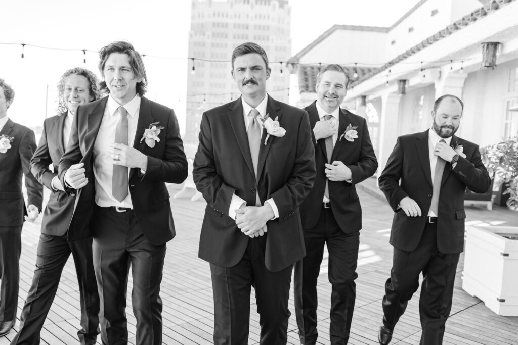 Groom and groomsmen walking on Sky Terrace rooftop at St. Anthony Hotel