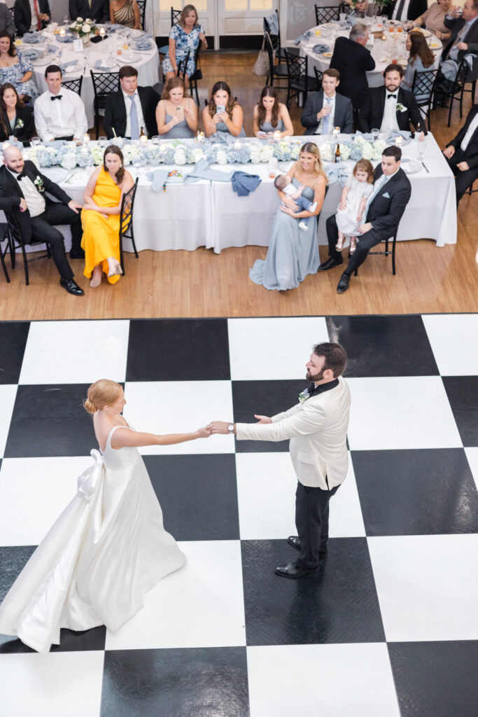 bride and groom have first dance on checkerboard dance floor