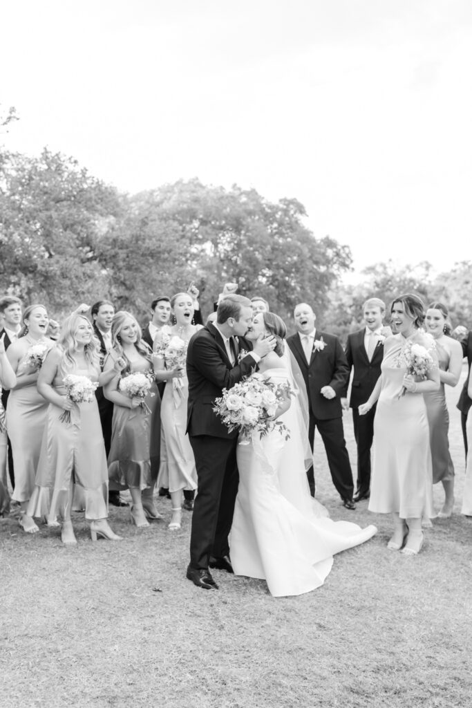 wedding party cheering for bride and groom while they kiss