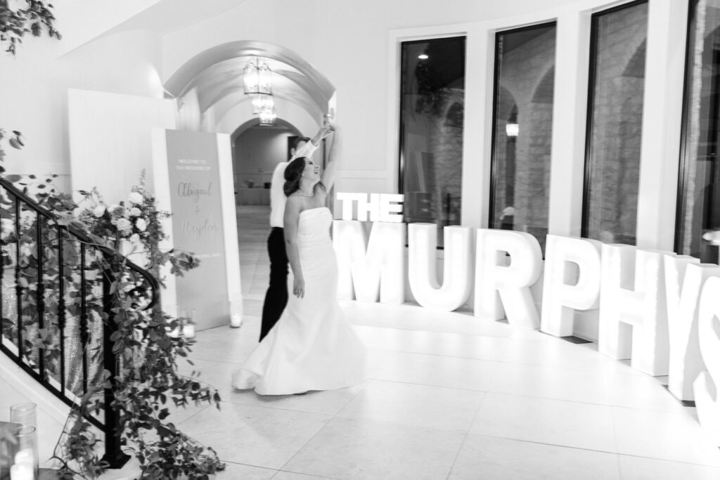 Bride and groom dancing in front of marquee letters