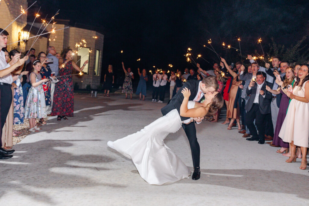 bride and groom dip kiss during sparkler exit