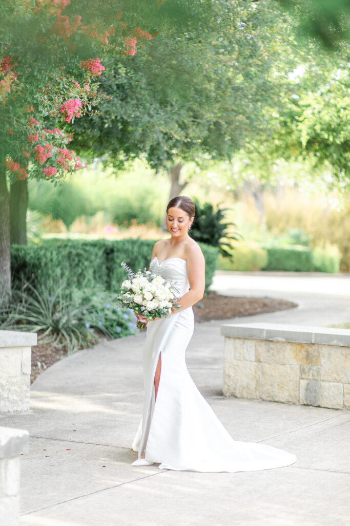 Bride at Landa Library smiling down at her white bouquet