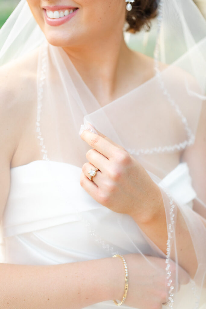 bride's bead embellished veil and diamond engagement ring