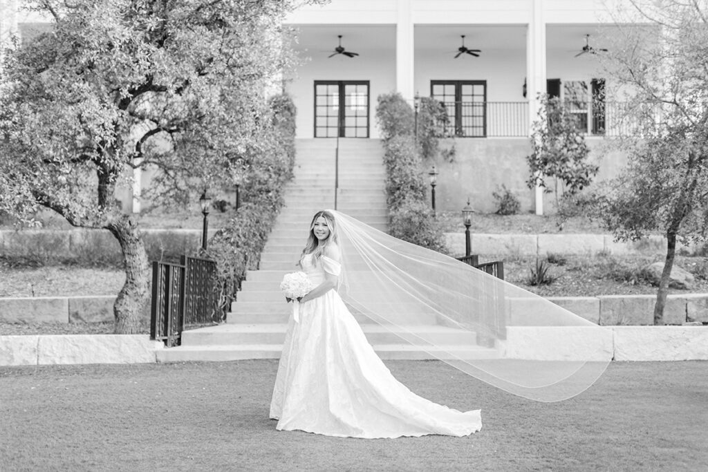 Bride's veil blowing in the wind with Kendall Point wedding venue in the background