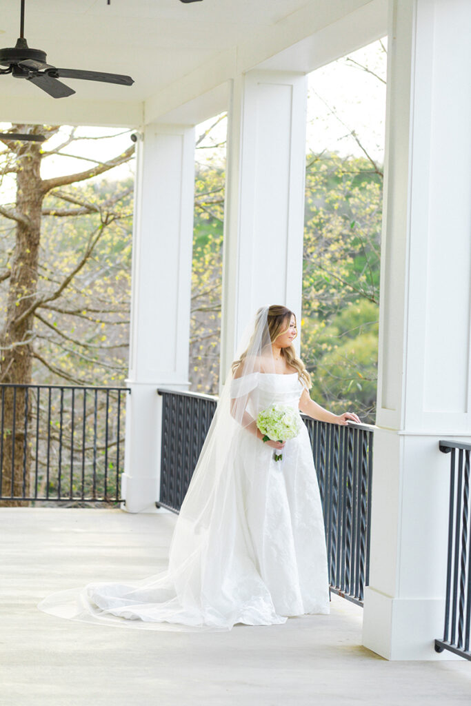 Bride looking off to the ceremony site from the Kendall Point wedding venue porch